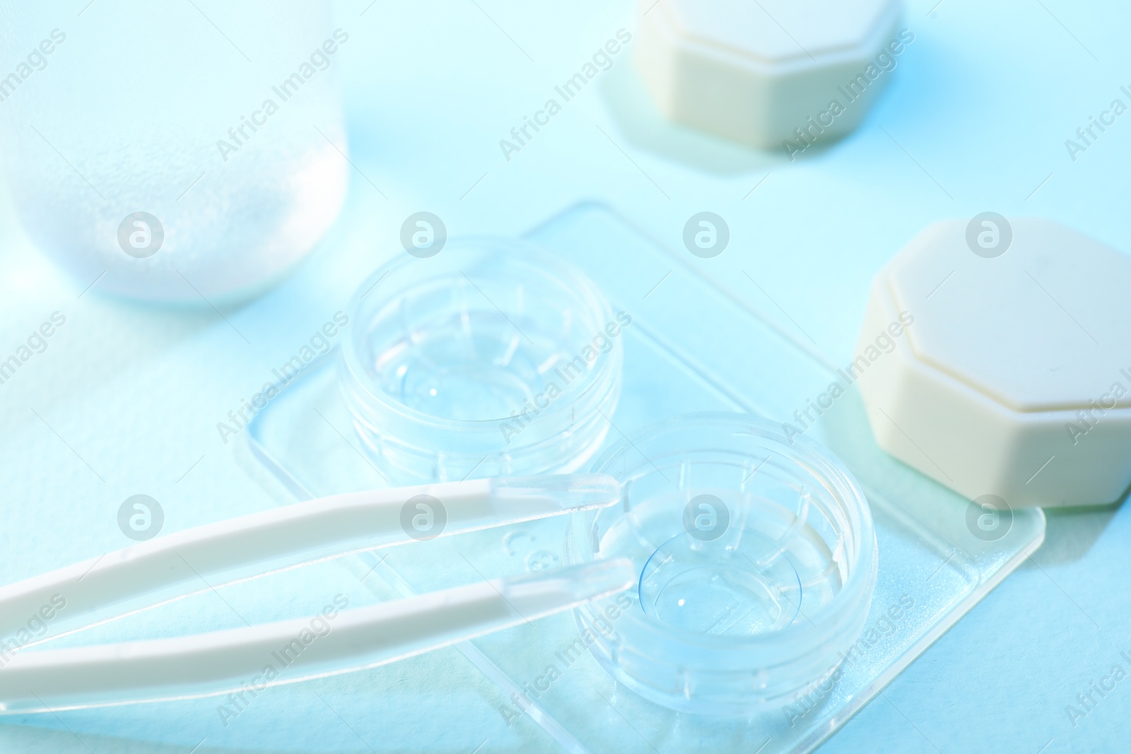 Case with contact lenses and tweezers on light blue background, closeup Photo of Case with contact lenses and tweezers on light blue background, closeup