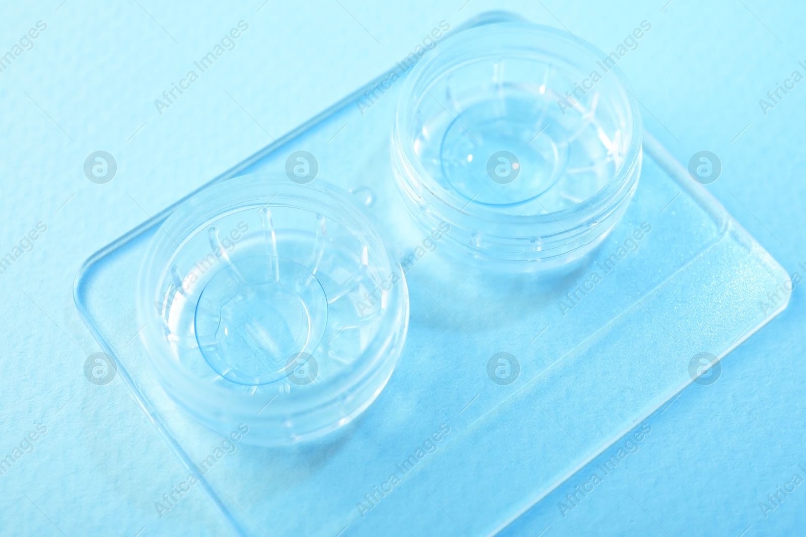Case with contact lenses on light blue background, closeup Photo of Case with contact lenses on light blue background, closeup