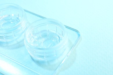 Photo of Case with contact lenses on light blue background, closeup