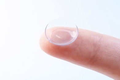 Photo of Woman with contact lens on light background, closeup