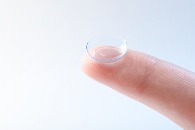 Photo of Woman with contact lens on light background, closeup. Space for text