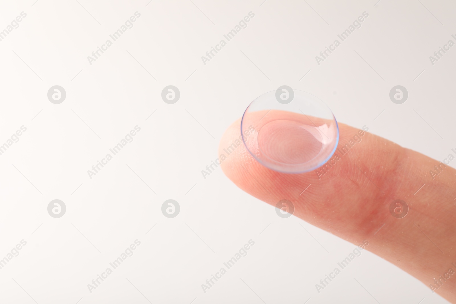 Woman with contact lens on light background, closeup. Space for text Photo of Woman with contact lens on light background, closeup. Space for text