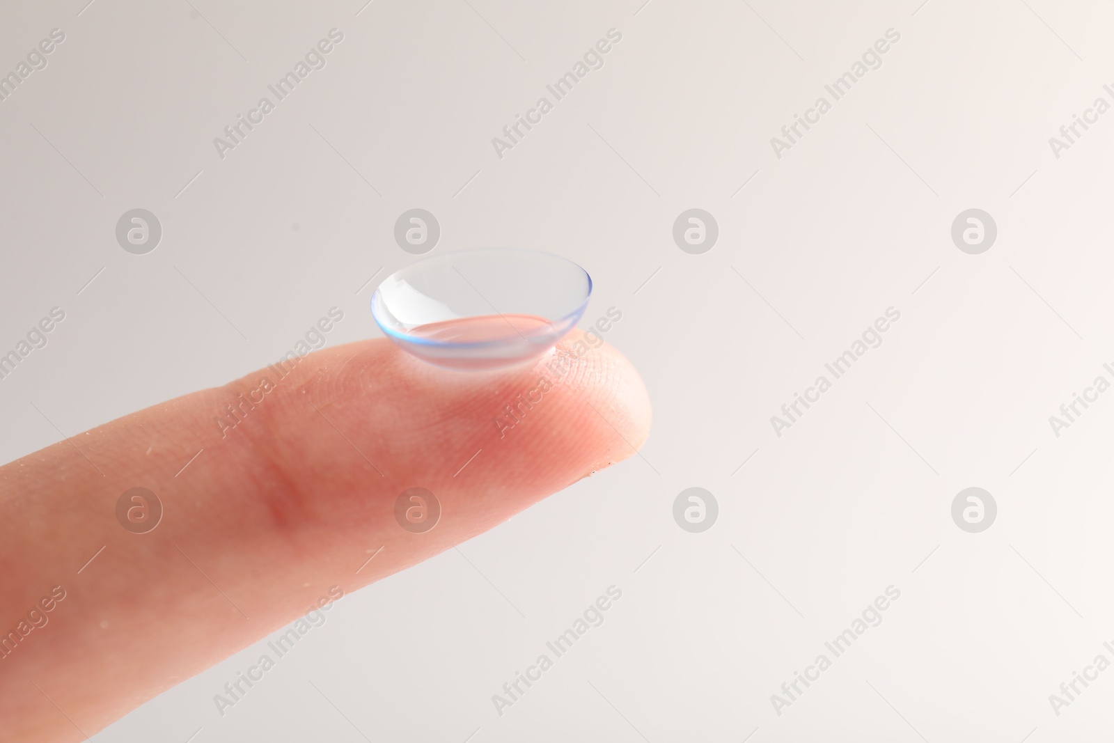 Woman with contact lens on light background, closeup. Space for text Photo of Woman with contact lens on light background, closeup. Space for text