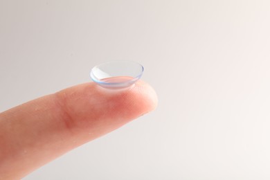 Photo of Woman with contact lens on light background, closeup. Space for text