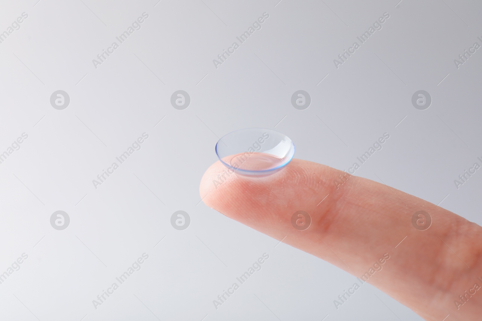 Woman with contact lens on light background, closeup. Space for text Photo of Woman with contact lens on light background, closeup. Space for text