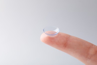 Photo of Woman with contact lens on light background, closeup. Space for text