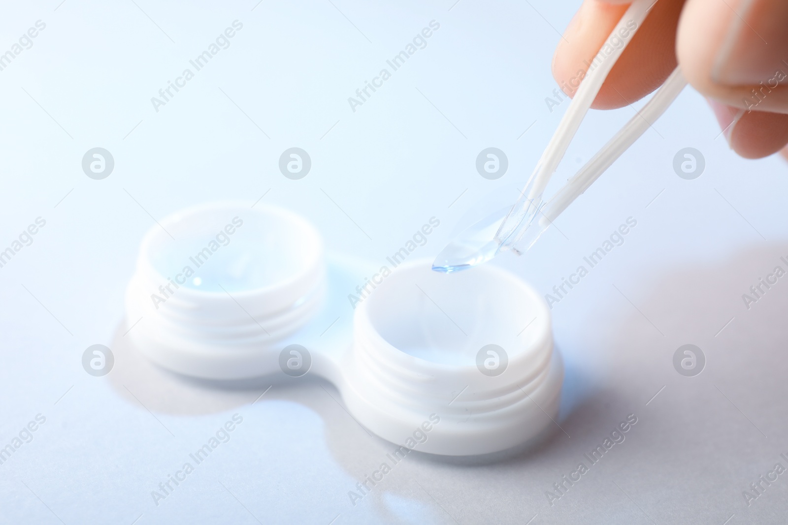 Woman taking contact lens out of case with tweezers on white background, closeup Photo of Woman taking contact lens out of case with tweezers on white background, closeup