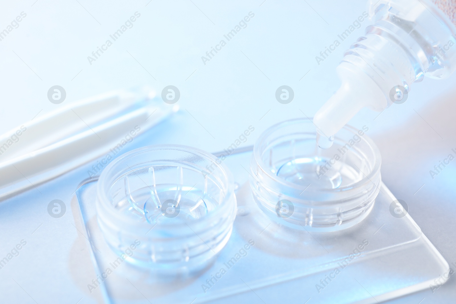 Dripping solution into case with contact lenses on light background, closeup Photo of Dripping solution into case with contact lenses on light background, closeup