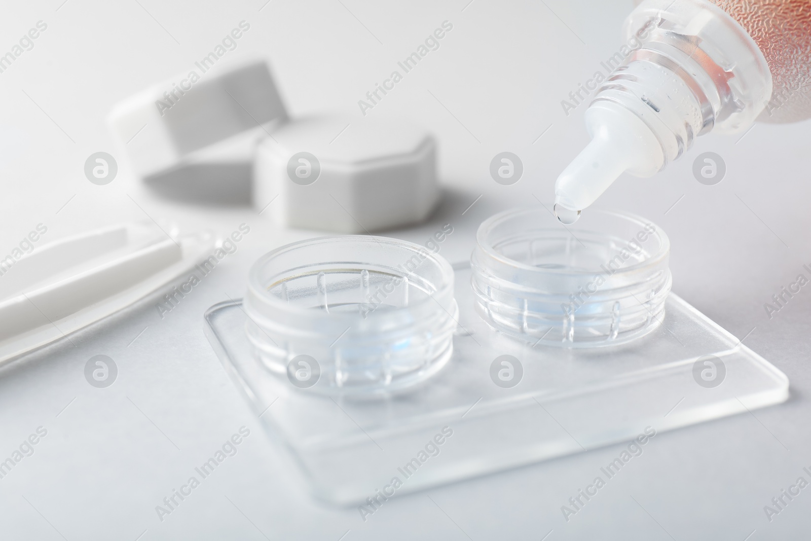 Dripping solution into case with contact lenses on light background, closeup Photo of Dripping solution into case with contact lenses on light background, closeup