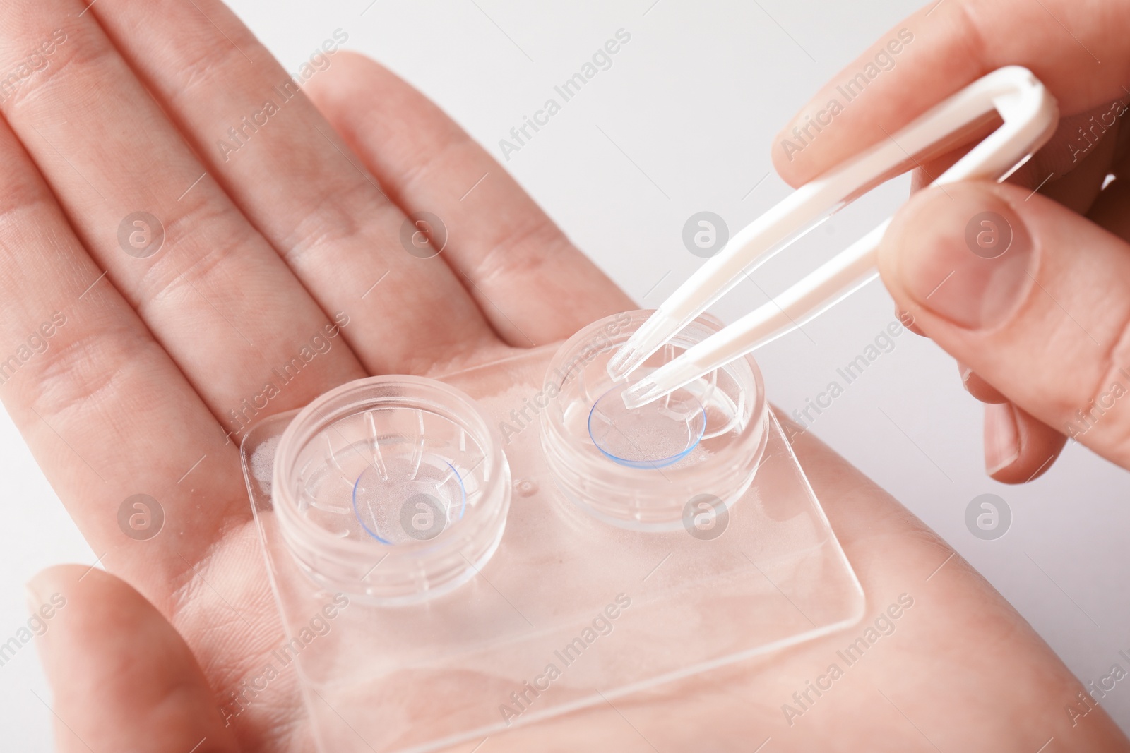 Woman taking contact lens out of case with tweezers on white background, closeup Photo of Woman taking contact lens out of case with tweezers on white background, closeup