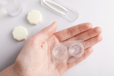 Photo of Woman with contact lenses on light background, flat lay