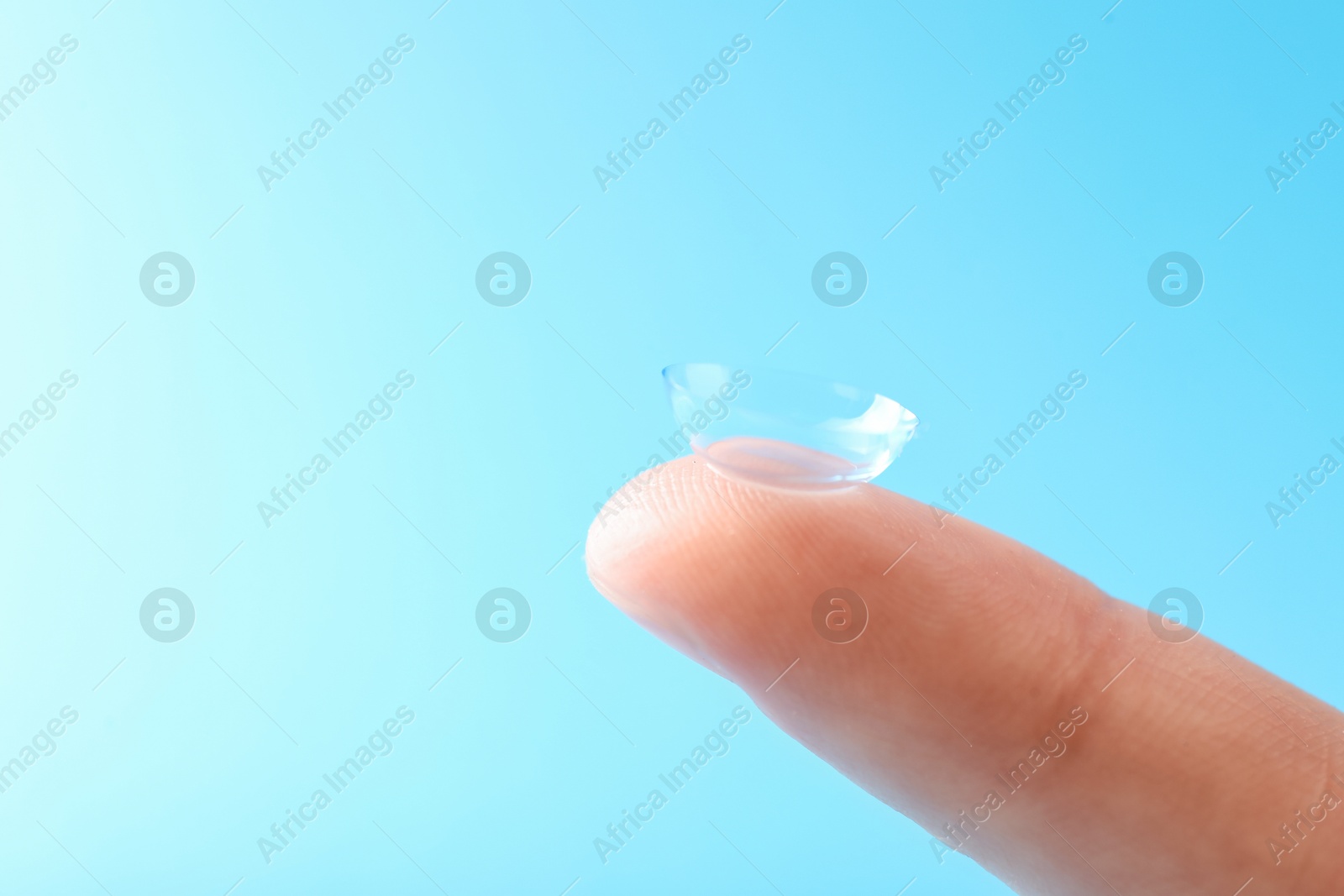 Woman with contact lens on light blue background, closeup. Space for text Photo of Woman with contact lens on light blue background, closeup. Space for text