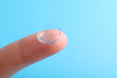 Photo of Woman with contact lens on light blue background, closeup. Space for text