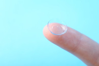 Photo of Woman with contact lens on light blue background, closeup. Space for text