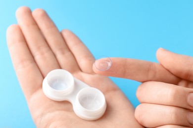 Photo of Woman with contact lenses on light blue background, closeup