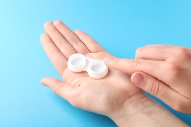 Photo of Woman with contact lenses on light blue background, closeup