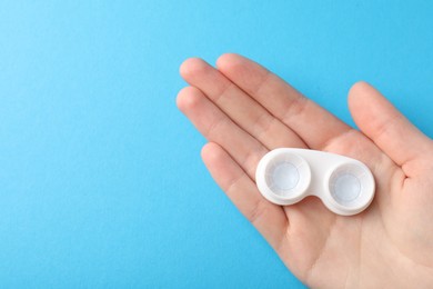 Photo of Woman with contact lenses on light blue background, top view. Space for text