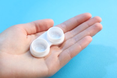 Photo of Woman with contact lenses on light blue background, closeup