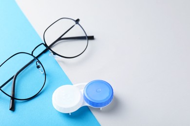 Photo of Case with contact lenses and glasses on color background, closeup. Space for text