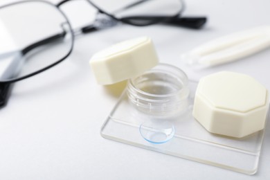 Photo of Case with contact lenses and glasses on white background, closeup