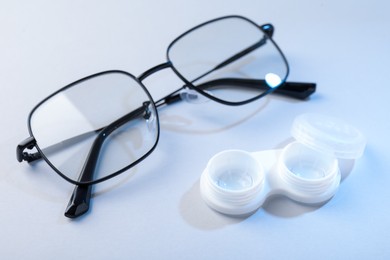 Photo of Case with contact lenses and glasses on white background, closeup