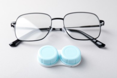 Photo of Case with contact lenses and glasses on white background, closeup