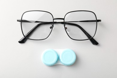 Photo of Case with contact lenses and glasses on white background, top view