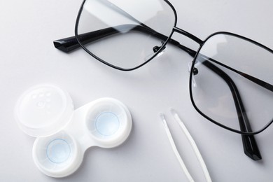Photo of Case with contact lenses, tweezers and glasses on white background, closeup
