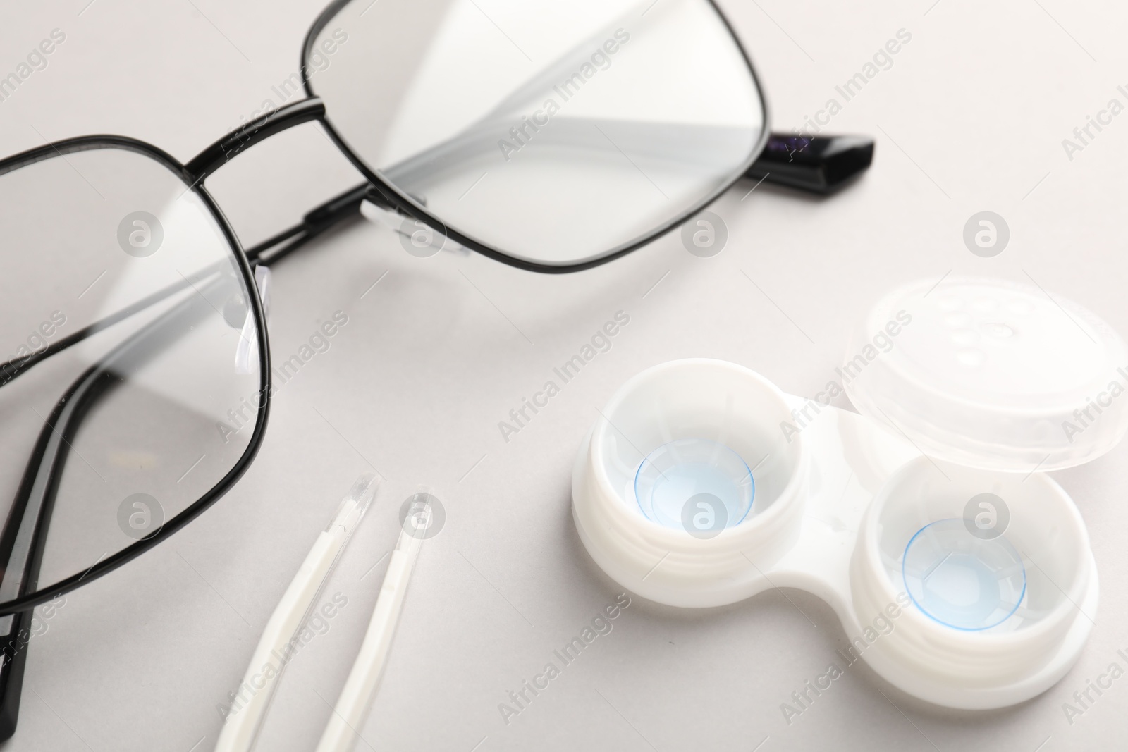 Case with contact lenses, tweezers and glasses on white background, closeup Photo of Case with contact lenses, tweezers and glasses on white background, closeup