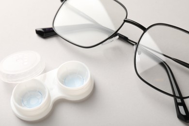 Photo of Case with contact lenses and glasses on white background, closeup
