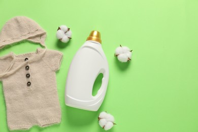 Photo of Bottle of fabric softener, cotton flowers and baby clothes on green background, flat lay. Space for text