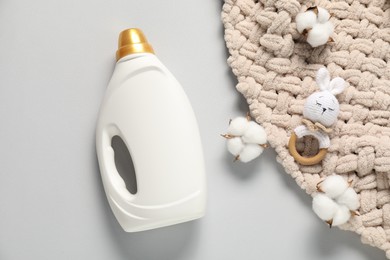 Photo of Bottle of fabric softener, toy, baby blanket and cotton flowers on light grey background, flat lay