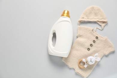 Photo of Bottle of fabric softener, toy and baby clothes on light grey background, flat lay. Space for text