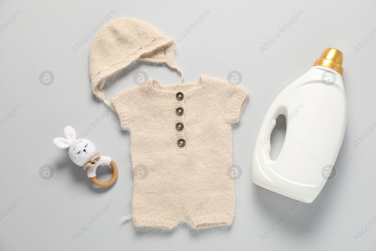 Bottle of fabric softener, toy and baby clothes on light grey background, flat lay Photo of Bottle of fabric softener, toy and baby clothes on light grey background, flat lay