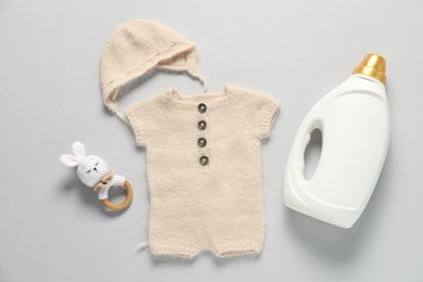 Photo of Bottle of fabric softener, toy and baby clothes on light grey background, flat lay