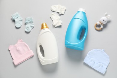 Photo of Bottles of fabric softener, toy and baby clothes on light grey background, flat lay