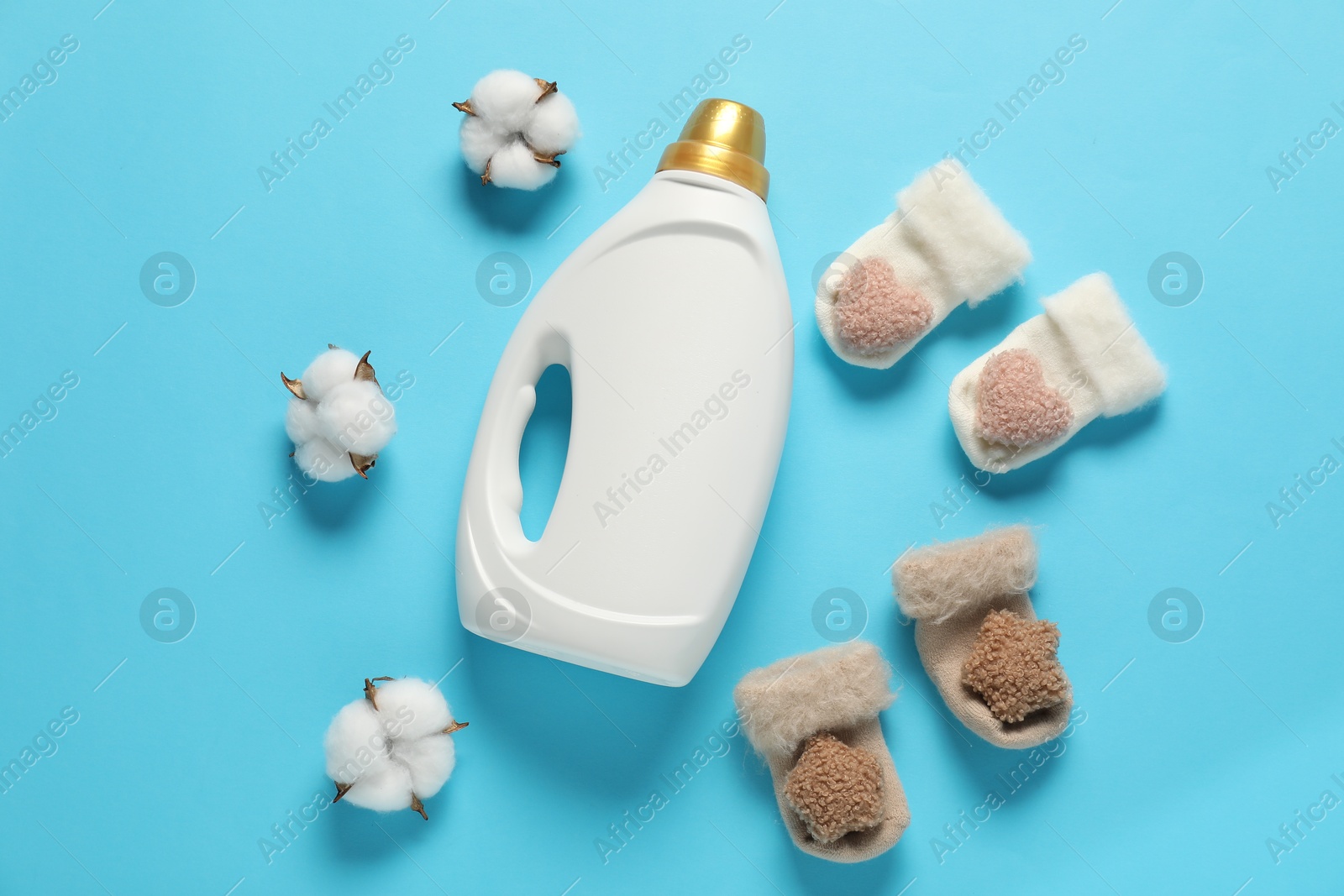 Bottle of fabric softener, cotton flowers and baby socks on light blue background, flat lay Photo of Bottle of fabric softener, cotton flowers and baby socks on light blue background, flat lay