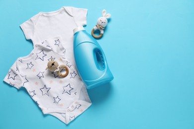 Photo of Bottle of fabric softener, toys and baby clothes on light blue background, flat lay. Space for text