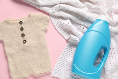 Photo of Bottle of fabric softener, baby clothes and blanket on pink background, flat lay