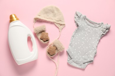 Photo of Bottle of fabric softener and baby clothes on pink background, flat lay