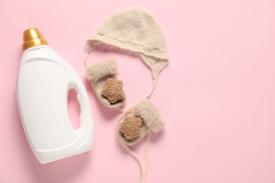 Photo of Bottle of fabric softener and baby clothes on pink background, flat lay. Space for text