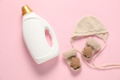 Photo of Bottle of fabric softener and baby clothes on pink background, flat lay