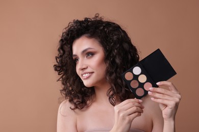 Photo of Smiling woman with eyeshadow palette on beige background