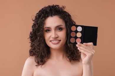 Photo of Smiling woman with eyeshadow palette on beige background
