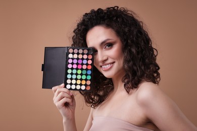 Photo of Smiling woman with eyeshadow palette on beige background