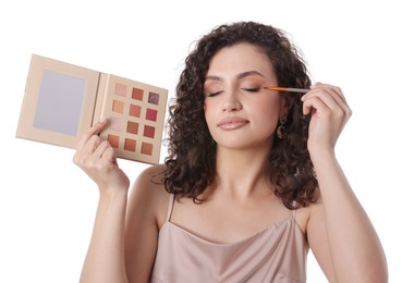 Photo of Woman with eyeshadow palette and brush applying makeup on white background