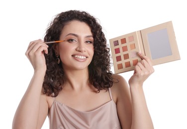 Photo of Smiling woman with eyeshadow palette and brush applying makeup on white background