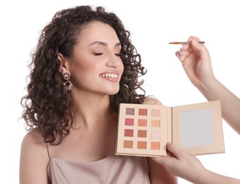 Photo of Makeup artist applying eyeshadows onto woman's face on white background, closeup