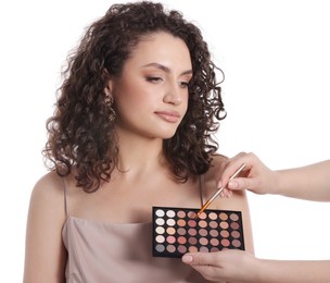 Photo of Makeup artist applying eyeshadows onto woman's face on white background, closeup