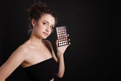 Photo of Woman with eyeshadow palette on black background. Space for text